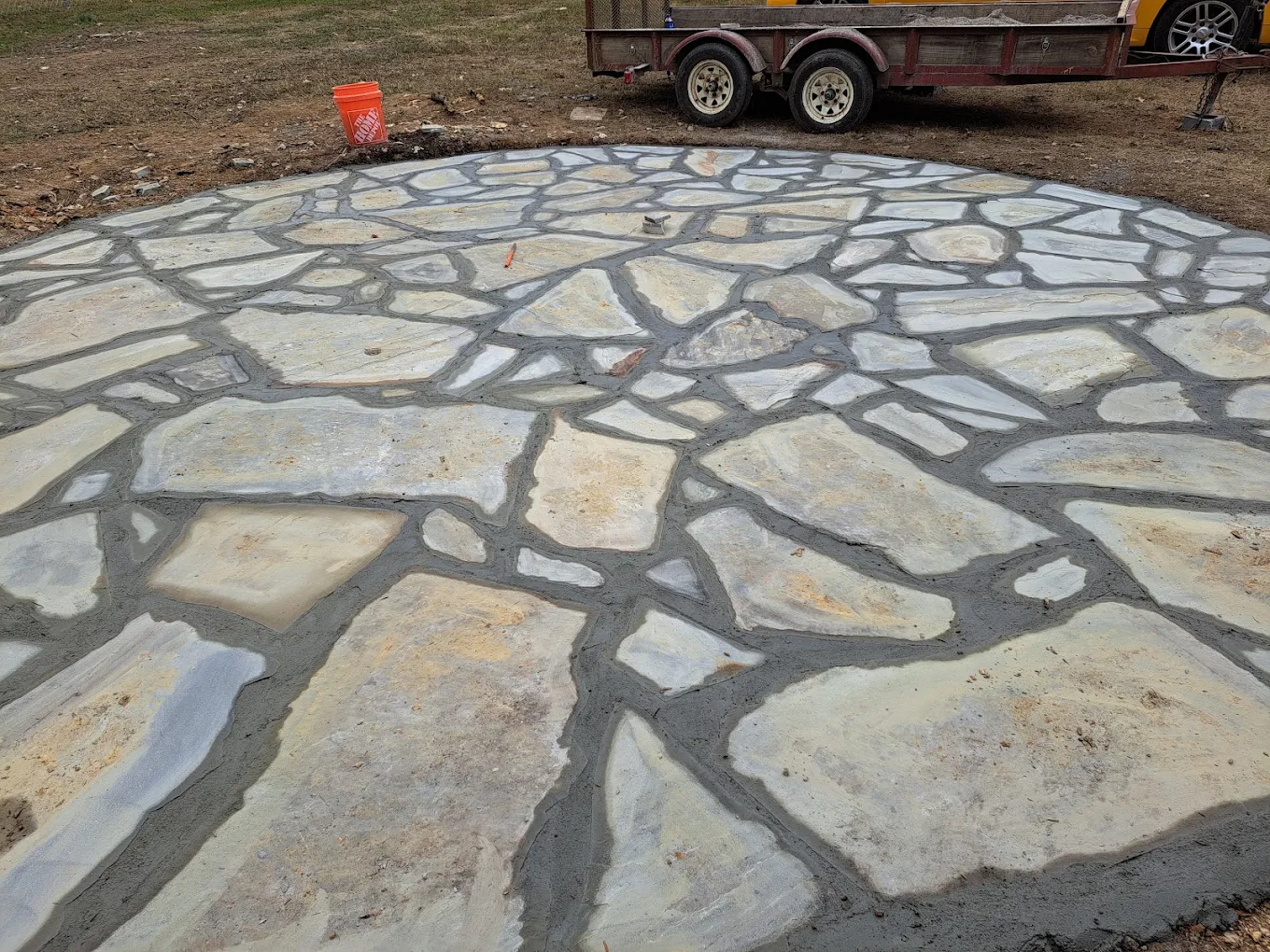 Newly installed flagstone patio with gray mortar joints and construction equipment in background
