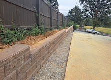 Newly installed retaining wall with gravel base along residential driveway