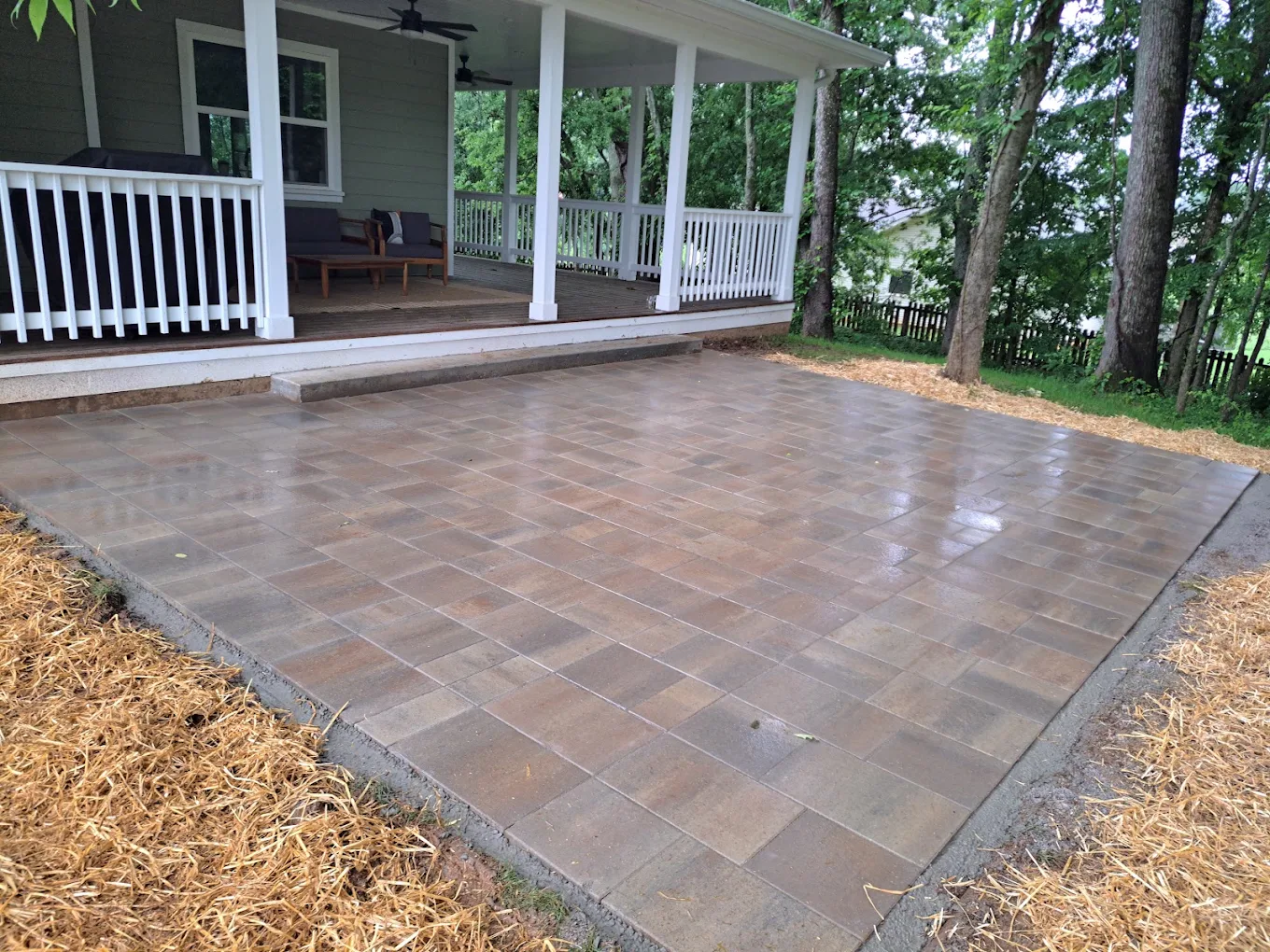 Newly installed paver patio in front of house with white columns and railing