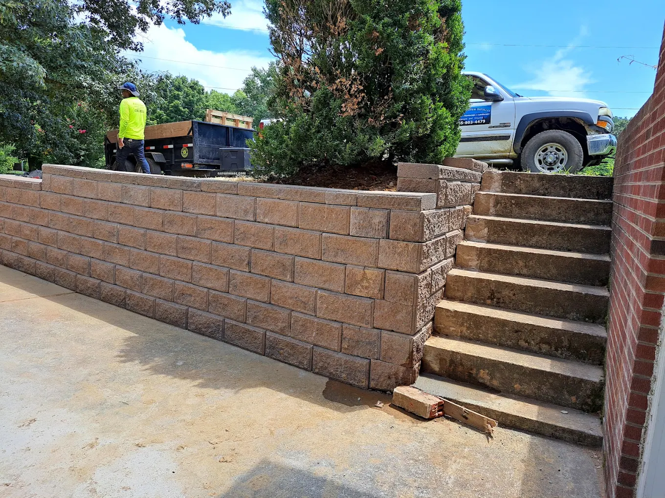 Retaining wall construction with worker and truck on residential property