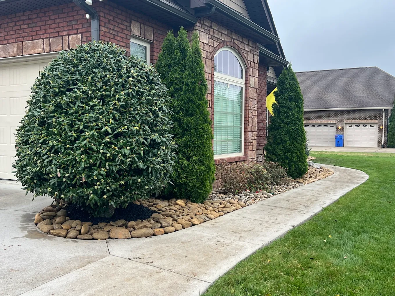 Brick home with manicured shrubs and river rock landscaping along front entrance