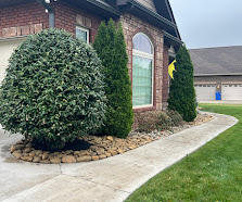 Brick house entrance with ivy-covered walls and arched doorway surrounded by landscaping