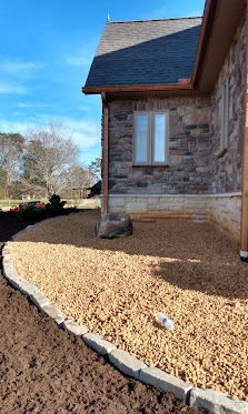 New stone house exterior with gravel landscaping and metal edging
