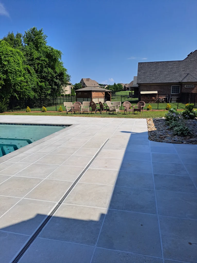Luxury backyard with pool, seating area, patio, and brick home under clear blue sky