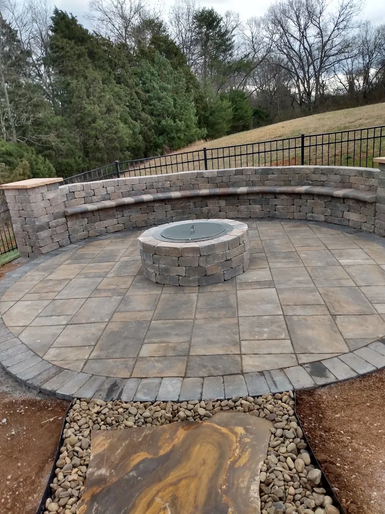 Circular patio with fire pit surrounded by curved stone seating wall and metal railing